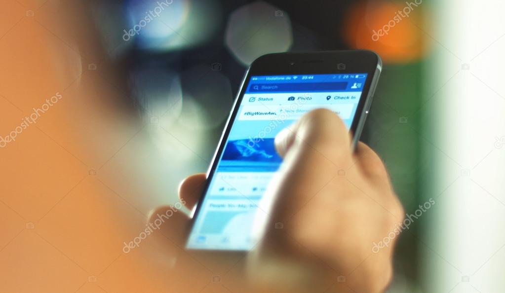 Aachen, Germany, September 28, 2015: close up shot of a young man uses facebook app on the new apple iphone 6s in the office