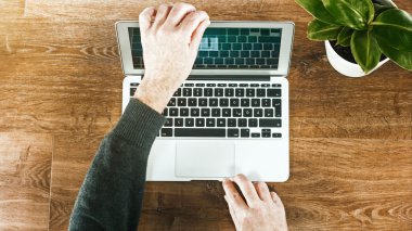 adam dizüstü ahşap bir masa üzerine kullanır.