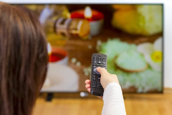 Jonge vrouw met tv remote en surfen programma 's — Stockfoto