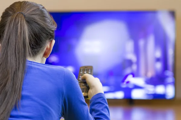 Девушка с дистанционным управлением смотрит умный телевизор — стоковое фото