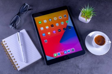 Galati, Romanya, 31 Mart 2021: Apple, A12 Biyonik çipi, Apple Kalem ve akıllı klavyeye destek olan 8. nesil iPad 'i piyasaya sürdü. Masaüstünde not defteri, kahve ve bardakları olan 8. nesil iPad.