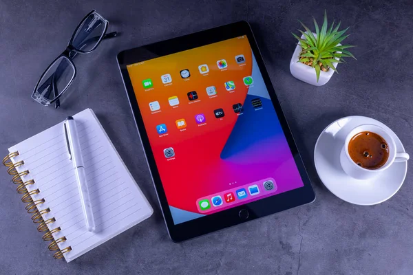 Galati, Romanya, 31 Mart 2021: Apple, A12 Biyonik çipi, Apple Kalem ve akıllı klavyeye destek olan 8. nesil iPad 'i piyasaya sürdü. Masaüstünde not defteri, kahve ve bardakları olan 8. nesil iPad.