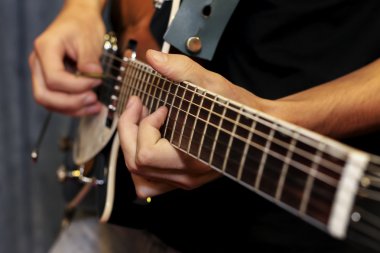 Elektro gitar yakın plan, parmaklarıyla çalıyor.