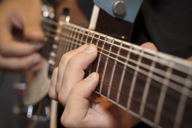 close up shot of a man with his fingers on the frets of a guitar clipart