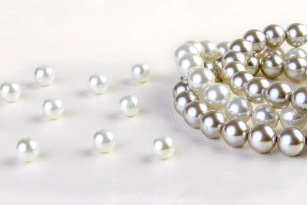Silberne und weiße Perlenkette auf weißem Papier — Stockfoto