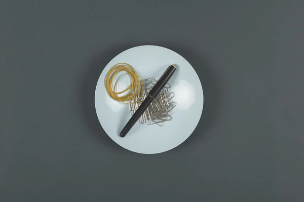 Ручка, резинки и скрепки на тарелке — стоковое фото