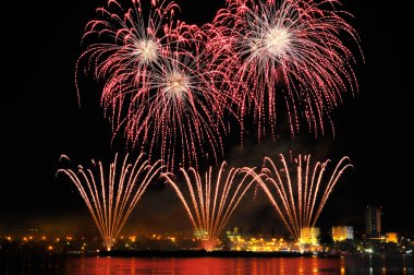 gece su yansıması ile şehir içinde havai fişek