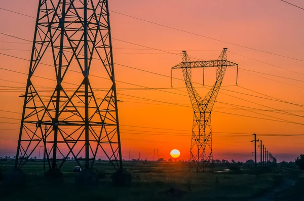 Pilones de electricidad de silueta durante la puesta del sol —  Fotos de Stock