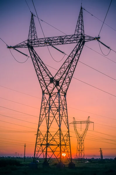 Pilones de electricidad de silueta durante la puesta del sol — Foto de Stock