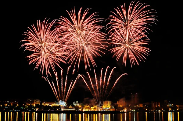 Firework over city at night with reflection in water — Stock Photo, Image