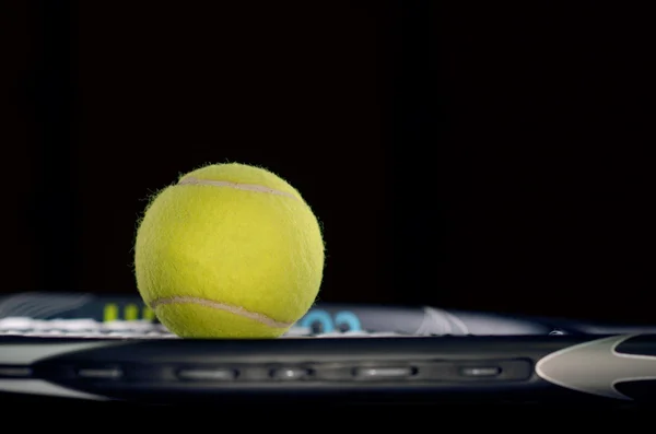 Raquete de tênis isolado em fundo preto com bola de tênis — Fotografia de Stock