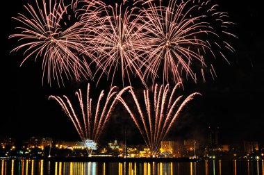 gece su yansıması ile şehir içinde havai fişek