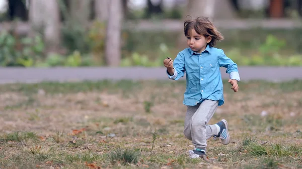 Bambino felice che corre attraverso il parco — Foto Stock