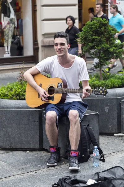 A young male street musician performing with his guitar in a square in Belgrade, the Serbian capital — Stock Photo, Image