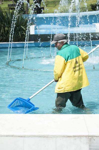 Trabajador municipal limpiando la piscina decorativa y las fuentes dentro del parque público Macka en Estambul —  Fotos de Stock