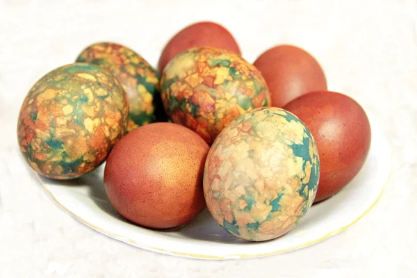Барвисті великодні яйця на білій тарілці, розміщеній на мисці — стокове фото