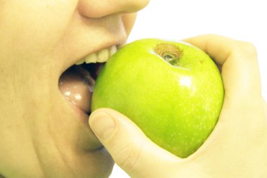 kadın üzerinde beyaz izole bir yeşil elma ısırdı