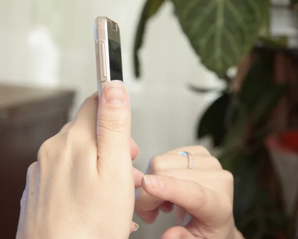 Рука жінки тримає смартфон і торкається екрана — стокове фото