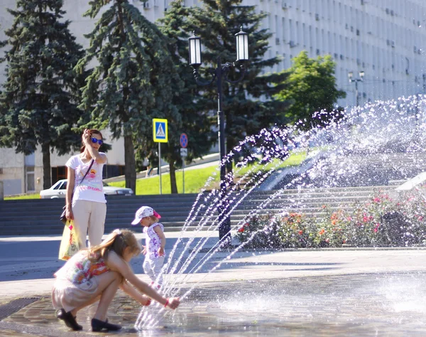 Children near a splashing fontain in the center of town — Stock Photo, Image