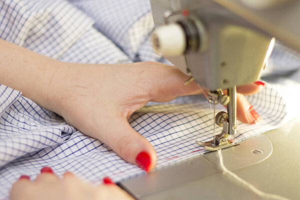 Женщина Тейлор работает над швейной машинкой крупным планом в скучной одежде