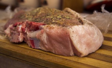 Kesme tahtasının üzerinde kemik ve baharat olan çiğ taze biftek.