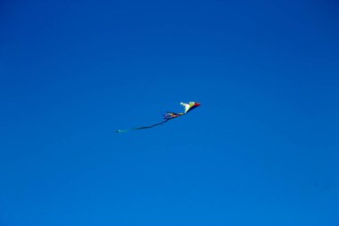 Mavi gökyüzünde uçan renkli bir uçurtma