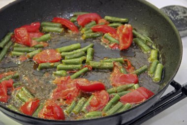 Domates ve yeşil fasulye kızartma tavasında kızartılmış sabah kızarmış yumurtalar yakın planda.