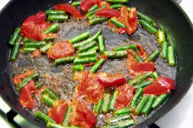 Domates ve yeşil fasulye kızartma tavasında kızartılmış sabah kızarmış yumurtalar yakın planda.