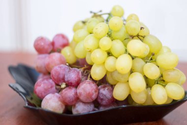 Kırmızı ve beyaz şarap. Siyah tabakta hazır üzüm var.