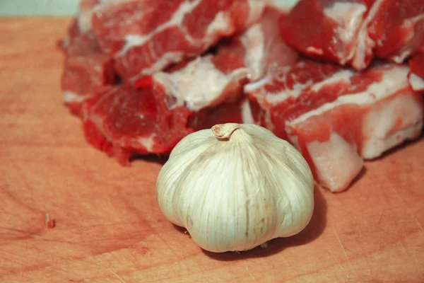 Carne fresca e alho fresco deitado na mesa da cozinha — Fotografia de Stock