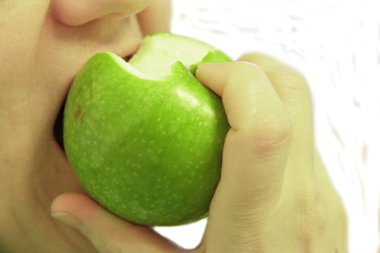 kadın üzerinde beyaz izole bir yeşil elma ısırdı