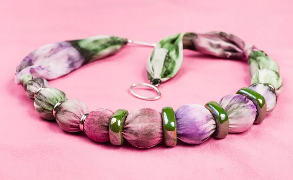 Ketting van zijden ballen en ceramische ringen op roze — Stockfoto