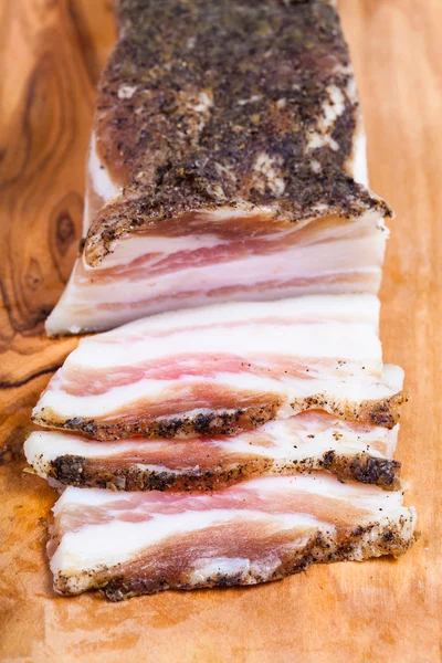 Peça e algumas fatias de bacon na tábua de corte — Fotografia de Stock