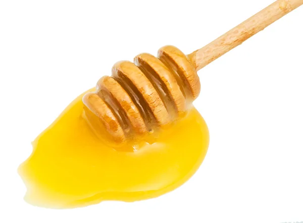 Puddle of yellow honey and wooden stick close up — Stock Photo, Image