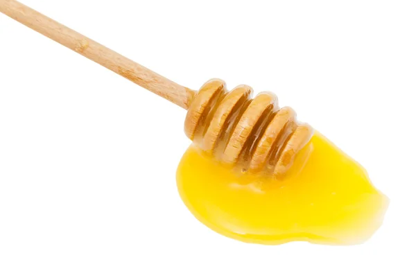 Poça de mel amarelo e colher de madeira de perto — Fotografia de Stock