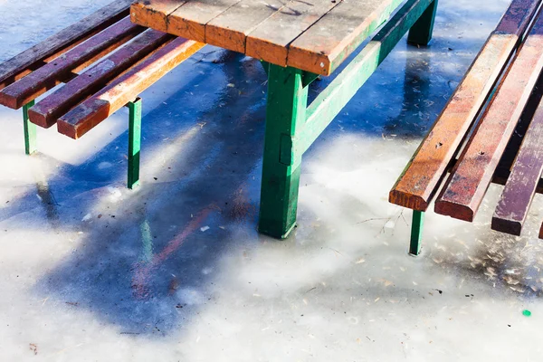 Table d'extérieur et bancs congelés dans la flaque d'eau — Photo