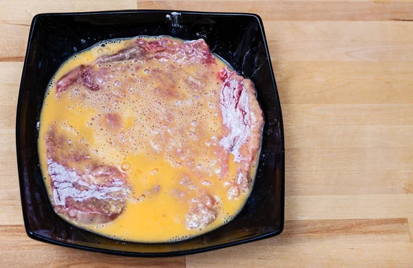 Schnitzel crudo de ternera empanado en huevos en un bol — Foto de Stock