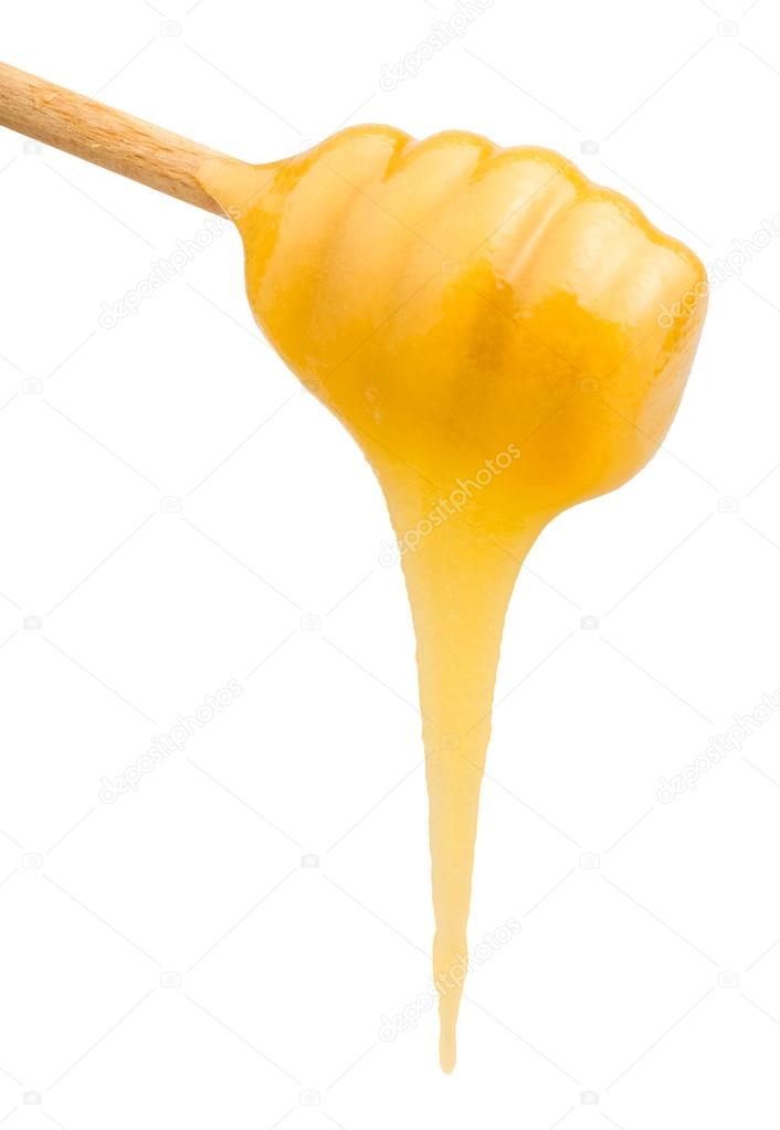yellow honey flows down from wooden spoon close up