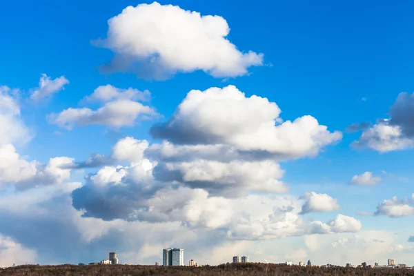 Kentsel evler üzerinde mavi gökyüzünde koca bulutlar — Stok fotoğraf