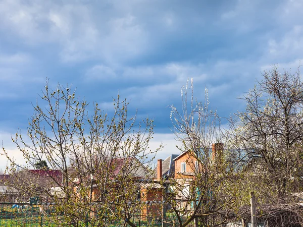 Clouds over country houses and cherry trees — Stock Photo, Image