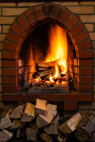 Pila de madera y troncos ardiendo en chimenea de ladrillo — Foto de Stock