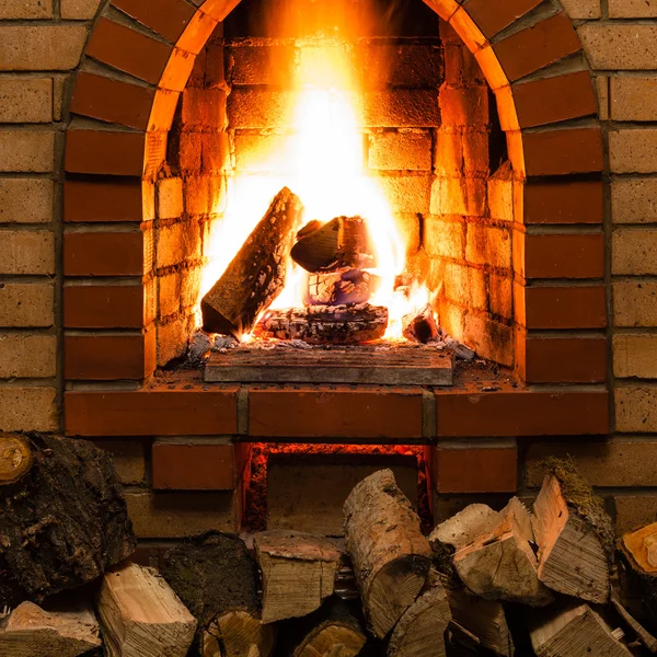 Stack of wood and tongues of fire in fireplace — Stock Photo, Image