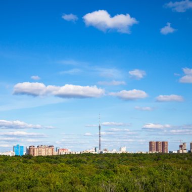 kasaba ve yeşil ağaçların üzerinde mavi gökyüzünde beyaz bulutlar