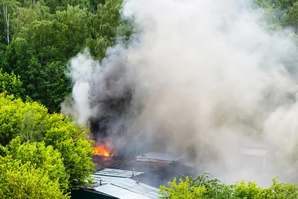 Střechy, oheň a šedý kouř v městské garáže za mokra — Stock fotografie