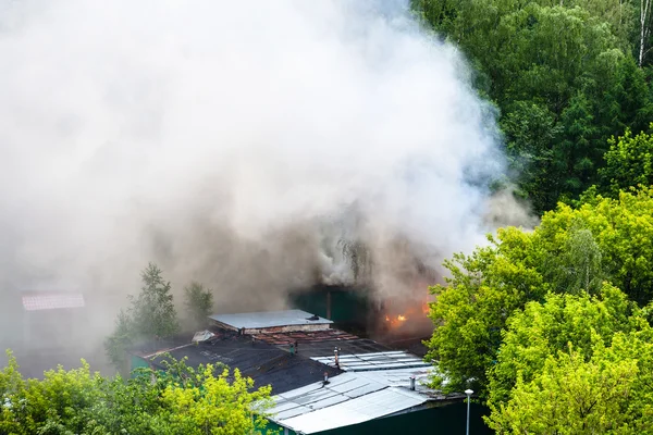 Techos húmedos, garaje en llamas y humo blanco — Foto de Stock