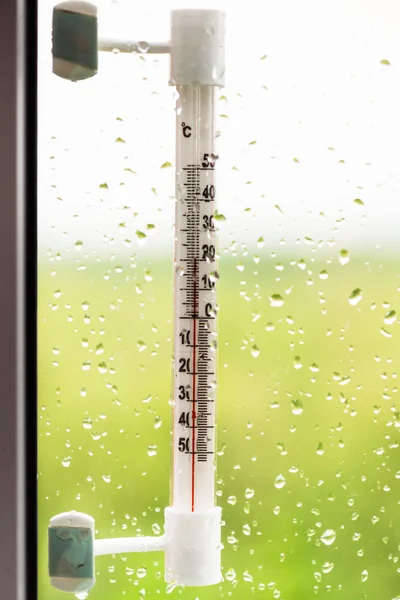 Thermometer und Regentropfen auf Fensterglas — Stockfoto