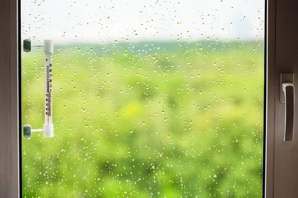 Ventana de inicio con gotas de lluvia y termómetro — Foto de Stock
