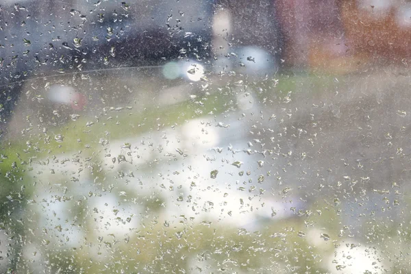 Gouttes de pluie sur vitre et rue urbaine floue — Photo