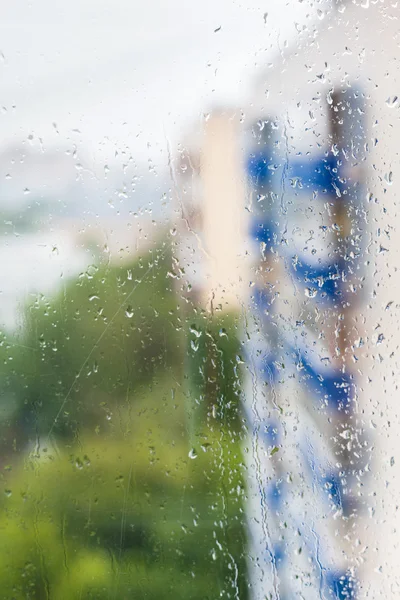 Gotas de lluvia en la ventana y casas de apartamentos borrosas —  Fotos de Stock