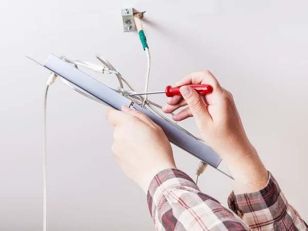 Électricien répare le câblage dans la lampe de plafond — Photo